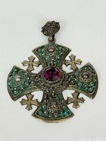 Front view of ornate silver Maltese cross pendant with purple stone