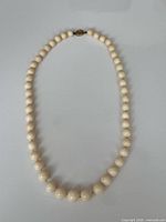 Full view of angel skin coral necklace laid flat