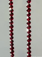 Close view of two portions of faceted garnet bead strand showing bead shape and color