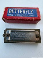 Miniature Butterfly harmonica front in front of original box, showing Butterfly brand and Occupied Japan mark