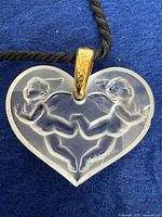 Front view of frosted crystal heart pendant with cherub motif and gold-tone bail