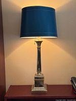 Full view of brass lamp with teal shade illuminated