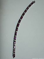 Full view of white gold bracelet showcasing alternating pink sapphires and diamond stations