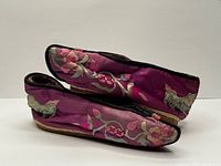 Side view of both lotus shoes showing magenta silk and embroidery