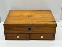 front view of closed mahogany jewellery box showing drawers, bone knobs and lock escutcheon
