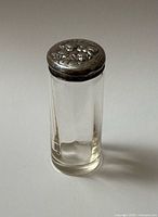 Full view of jar standing upright showing glass body and silver lid