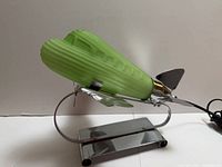 Left side view showing green ribbed glass shade and chrome airplane body on stand