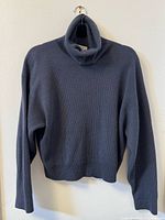 Front view of dusty blue turtleneck sweater on hanger