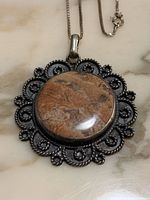 Front view of pendant showing stone and silver detailing with attached chain