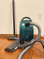 Front view of canister vacuum with hose, wand and floor head displayed