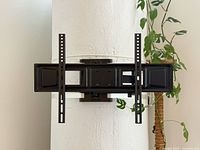 Black metal TV mount strapped around a white column with two white ratchet straps