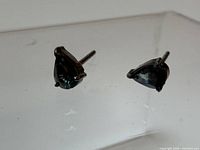 Close view of both stud earrings showing stone color and setting