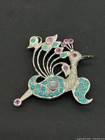 Front view of silver-tone peacock brooch with turquoise and pink stones