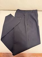 Folded trousers showing white stitching detail on leg