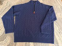 Full view of navy cable knit half-zip sweater laid flat