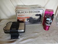 Lot overview showing Black+Decker waffle maker box, Cooks waffle maker, Primula 20oz thermal tumbler