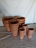 All twenty-one terracotta pots nested by size on cloth backdrop