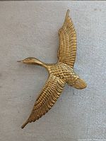 Front view of gold-tone flying bird doorstop
