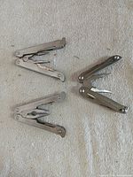 Three folding plier multi-tools opened on cloth surface