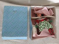 Open box showing Madame Alexander doll dressed in red/green outfit, original tissue and box lid
