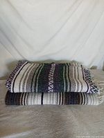Both folded Mexican blankets stacked, showing fringe ends