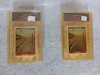 Both sealed trading card sets side by side in gold clamshell packaging