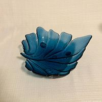 Angled view of blue glass leaf bowl showing form and texture