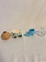 Group shot of four trinkets: brown vase, stagecoach planter, blue boot, clear glass vase