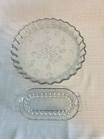 Both clear glass pieces side by side: round Savannah quiche pan above oval Candlewick serving dish below.