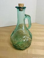 green embossed glass decanter front view with cork