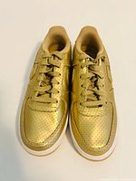 Top view of Nike Air Force 1 SP metallic gold sneakers showing perforated leather uppers and laces