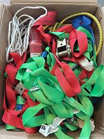 Box containing assorted red and green ratchet straps with metal ratchets and cords