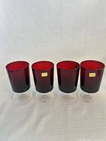 Four ruby red stemmed glasses front view with clear bases, labels visible