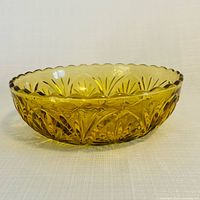 Side profile of an amber pressed-glass bowl showing scalloped rim and petal pattern