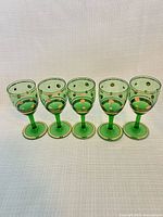 Front view of five green mini goblets showing gold polka dots and foot bands