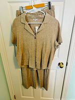 Front view of shirt hung over matching pants, tags visible