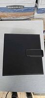 Closed black faux-leather CD binder with stitched edges and flap