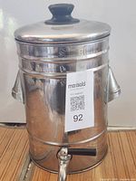 Front view of stainless steel water container with lid and spigot