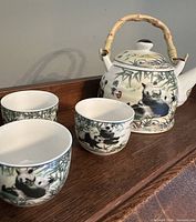 Teapot front and three cups illustrating panda design