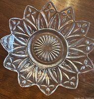 Top view of one pressed-glass dish showing floral sunburst design