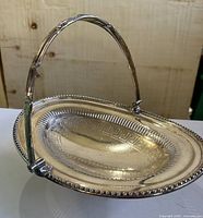Side view of silver-plated platter showing folding handle and pedestal foot