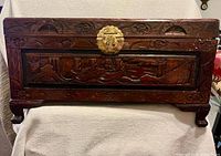 Front view of carved wooden chest showing brass clasp and sailboat scene panel
