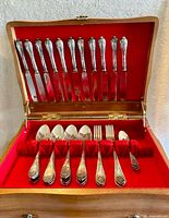 Open wooden case showing full set of knives, spoons, forks