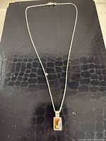 Full view of sterling silver necklace with rectangular amber pendant