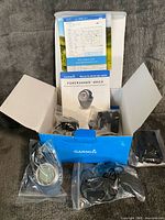 Open Garmin box showing watch, accessories in bags, manual