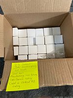 Open carton containing 32 small white boxes and bagged hardware
