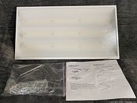 Front view of LED high bay luminaire with hardware bag and instructions