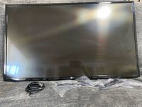 Front view of LG 42" TV with power cord and bagged stand legs