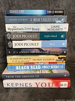 Stack of ten paperback novels showing spines for title and author identification