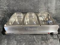 Front view showing Waring Pro stainless buffet server with three clear lids in place
